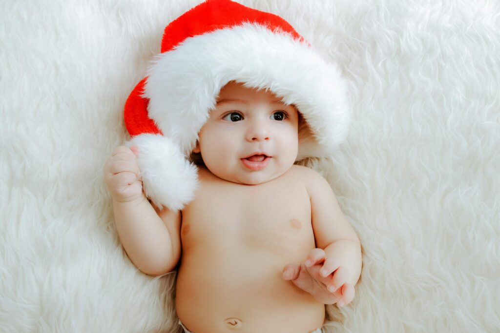 Charming infant wearing a Santa hat, lying on a fluffy blanket, perfect for holiday themes.