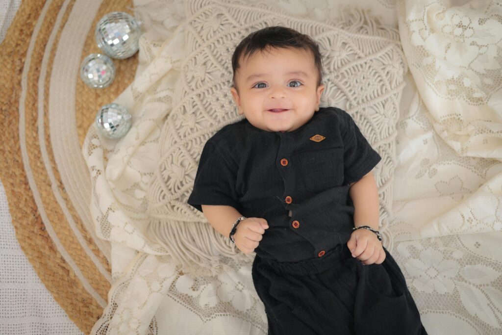 Cute baby lying on a blanket with decorative balls and a big smile.