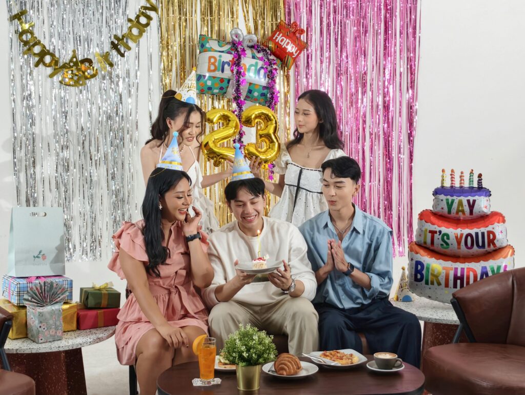 Group of friends celebrating a birthday indoors with gifts and cake in Jakarta.